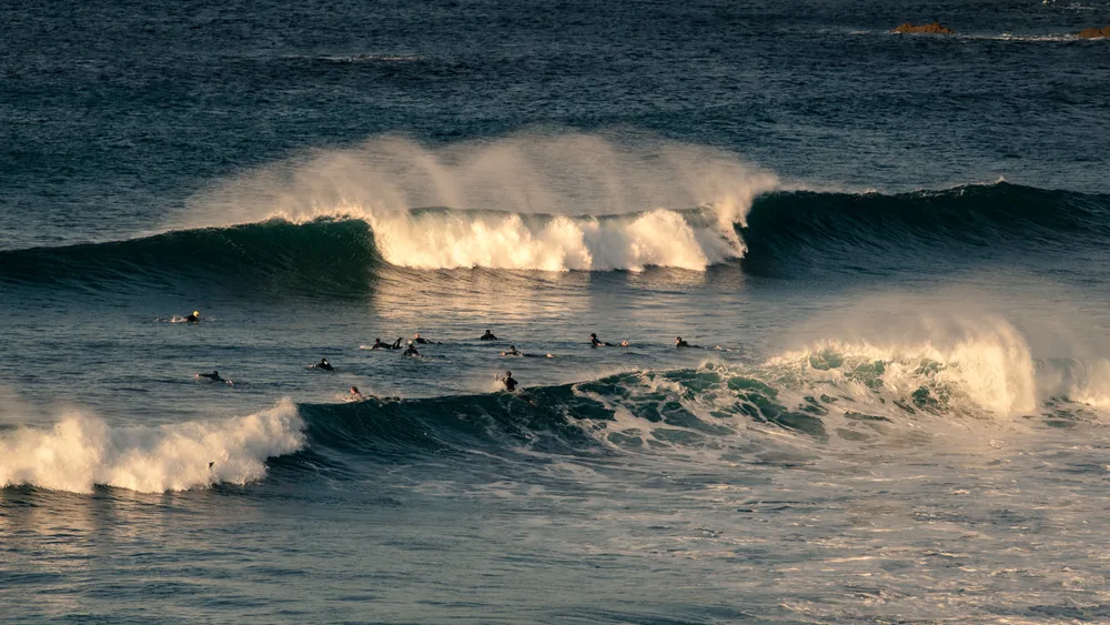 A set wave breaking through a lineup of surfers in winter light, San Sebastián, Spain